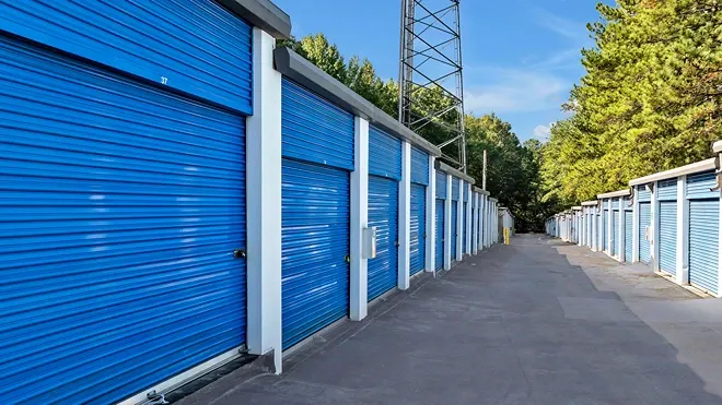 Row of drive-up storage units with blue roll-up doors and wide access lane at Devon Self Storage